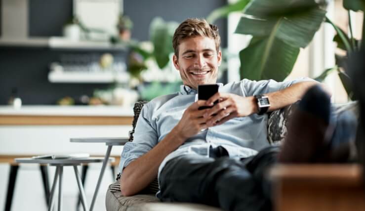 man on couch looking at mobile device